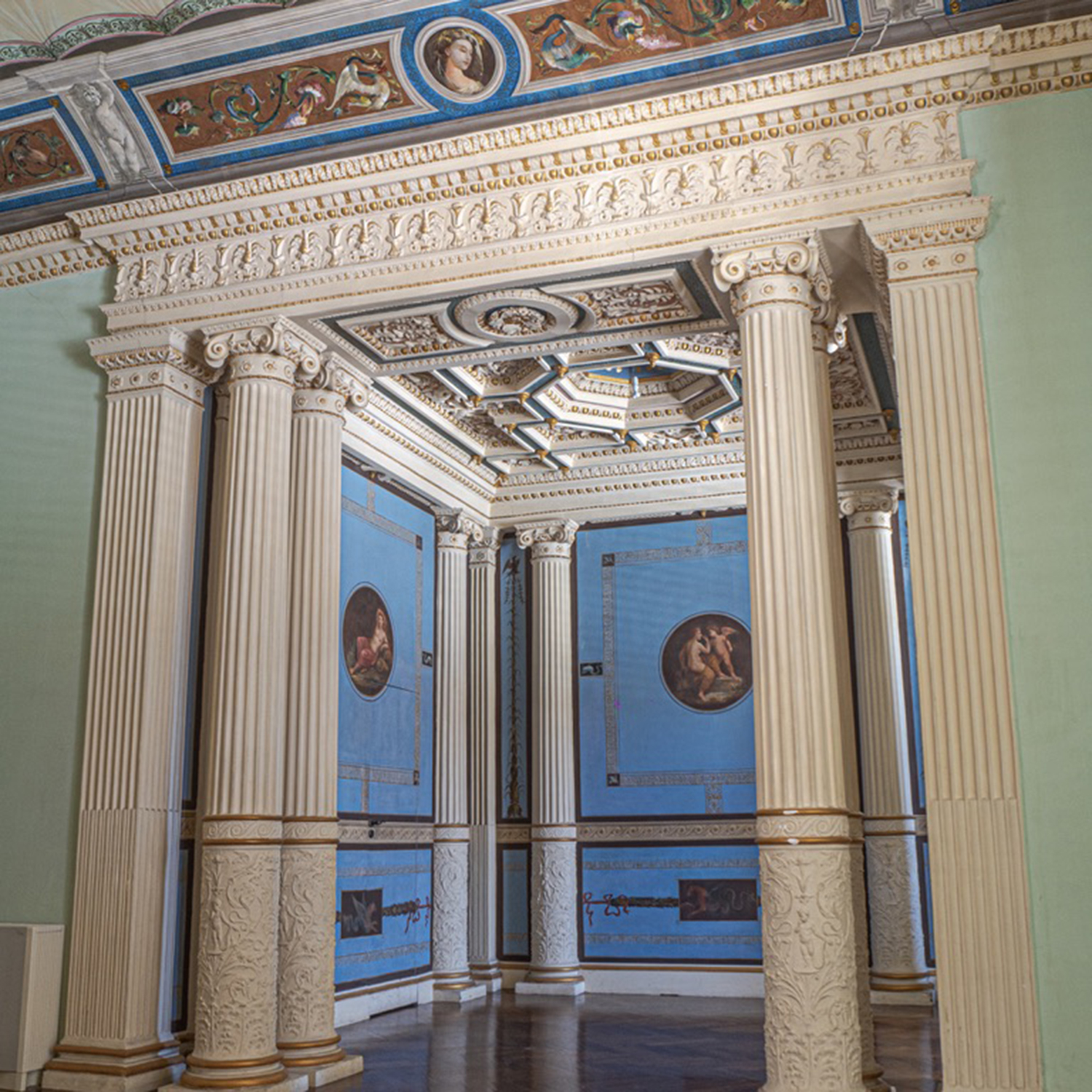 Ambiente del piano nobile di Palazzo Bonocore, con soffitto affrescato e portale d'ingresso in una stanza, delimitato da colonne.